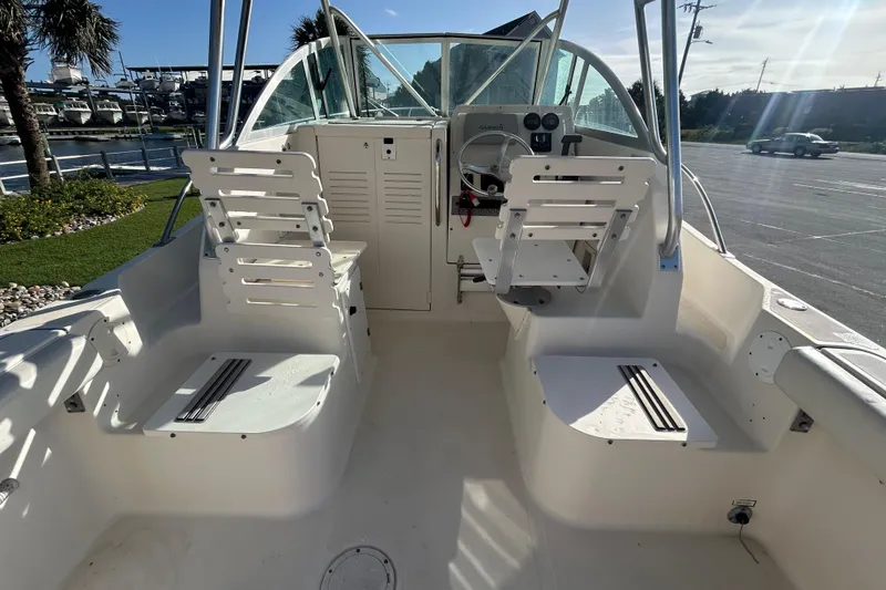Slide: The Image of 2000 Pursuit 2470 Walkaround boat interior with seating and steering wheel, docked near marina. - 11