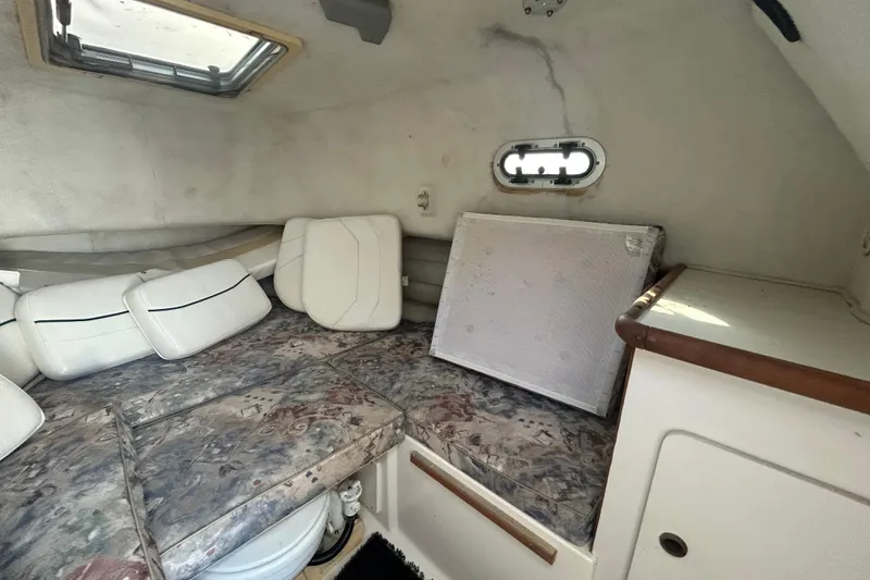 Slide: The Image of 2000 Pursuit 2470 Walkaround cabin interior with cushions and storage space. - 21