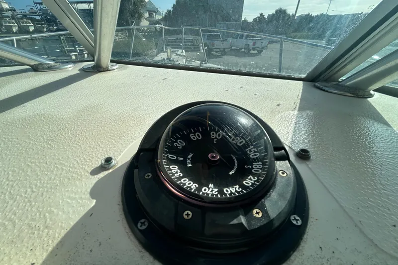 Slide: The Image of Compass on 2000 Pursuit 2470 Walkaround boat dashboard, with outdoor view. - 22