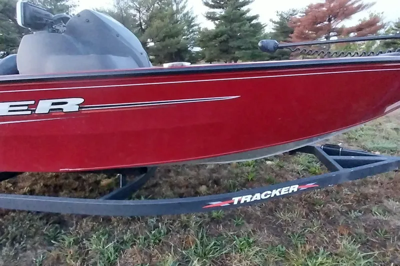 Slide: The Image of Red 2021 Tracker Super Guide V-16 SC boat on trailer, parked on grass. - 2