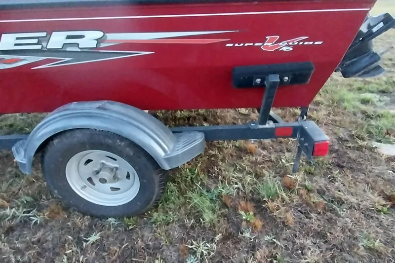 Slide: The Image of 2021 Tracker Super Guide V-16 SC boat trailer on grass, showcasing rear wheel and fender. - 25