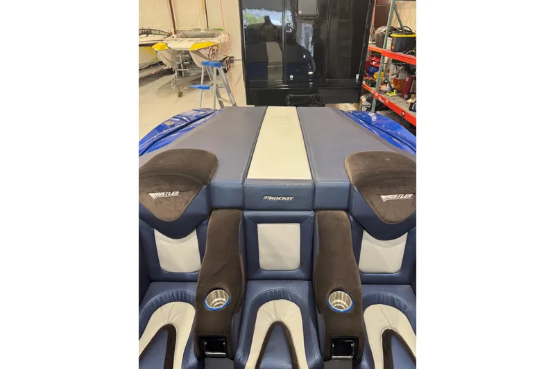 Slide: The Image of 2016 Hustler 39 boat interior with blue and beige seating in a workshop. - 16