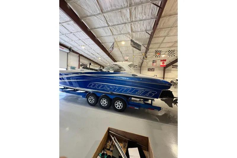 Slide: The Image of Blue 2016 Hustler 39 boat on trailer in indoor storage facility. - 2