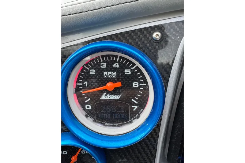 Slide: The Image of Close-up of a 2016 Hustler 39 RPM gauge with blue trim and carbon fiber background. - 22