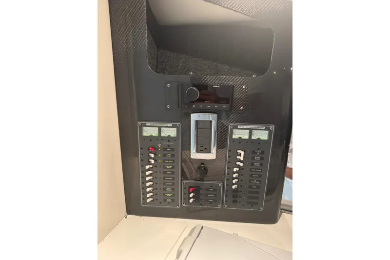 Slide: The Image of Control panel of a 2016 Hustler 39 boat with switches and gauges. - 23