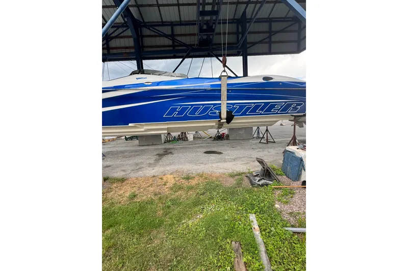 Slide: The Image of 2016 Hustler 39 boat in blue, suspended in a boatyard. - 4