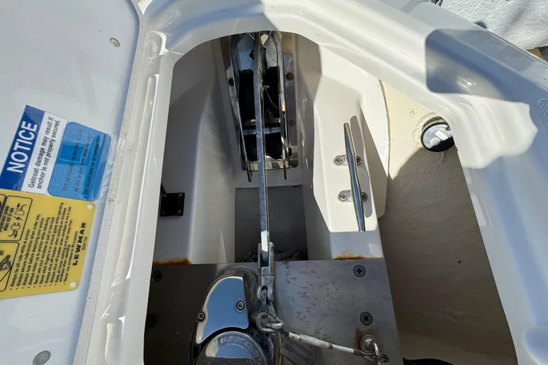Slide: The Image of 2022 Pursuit DC 266 Dual Console anchor compartment with safety notices and hardware. - 10