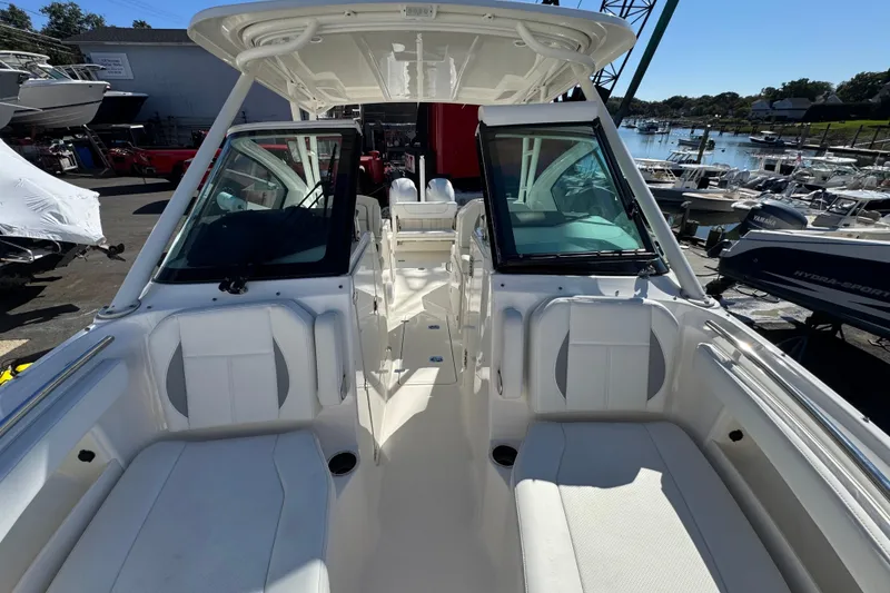 Slide: The Image of 2022 Pursuit DC 266 Dual Console boat interior with seating and helm, docked at marina. - 11