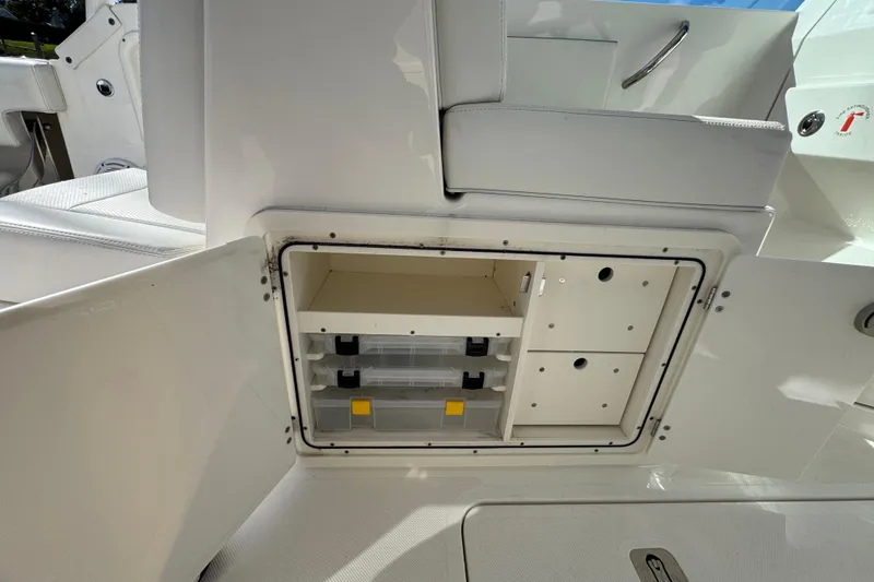 Slide: The Image of 2022 Pursuit DC 266 Dual Console boat storage compartment with open door and organized shelves. - 14