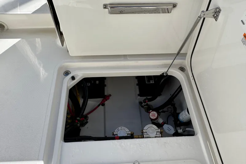 Slide: The Image of 2022 Pursuit DC 266 Dual Console boat storage compartment with visible wiring and components. - 3
