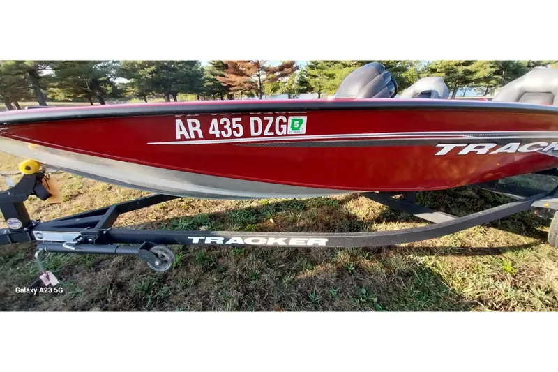 Slide: The Image of 2024 Tracker Pro Team 175 TXW boat on trailer, red exterior, parked on grass. - 17