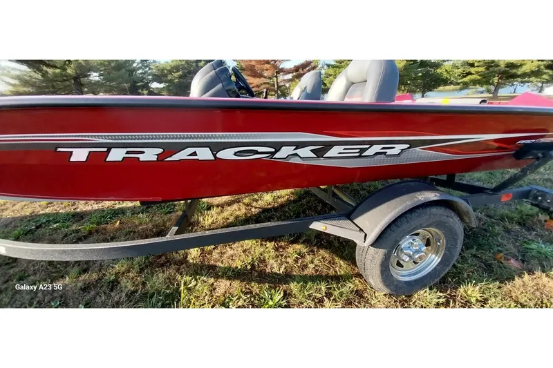 Slide: The Image of 2024 Tracker Pro Team 175 TXW boat on trailer, red exterior, parked on grass. - 20