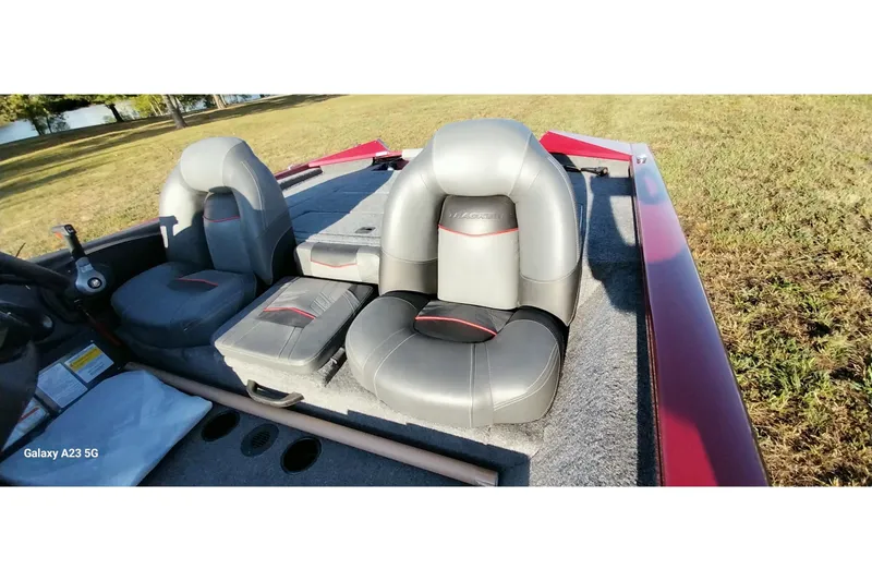 Slide: The Image of 2024 Tracker Pro Team 175 TXW boat interior with gray seats on grassy area. - 23