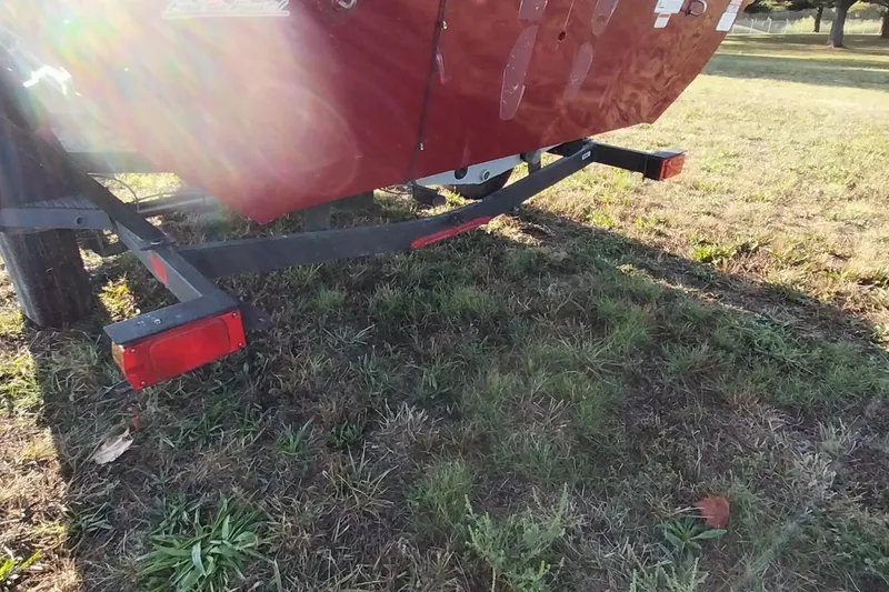 Slide: The Image of 2024 Tracker Pro Team 175 TXW boat trailer on grassy field, sunlight reflecting. - 28