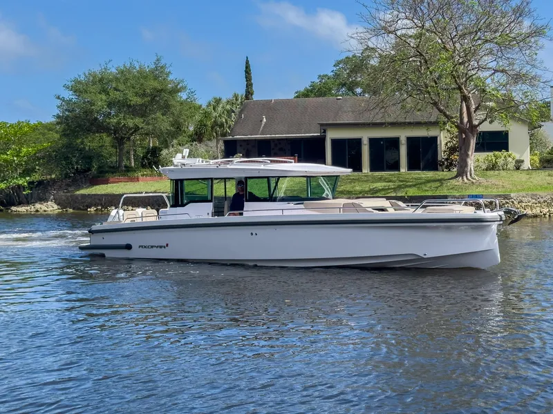 Slide: The Image of 2024 Axopar 37XC CROSS CABIN boat cruising on a calm river near a house. - 40