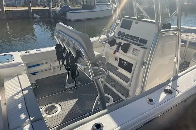 Slide: The Image of 2023 Sea Fox 228 Commander boat interior with helm and seating, docked by the water. - 1