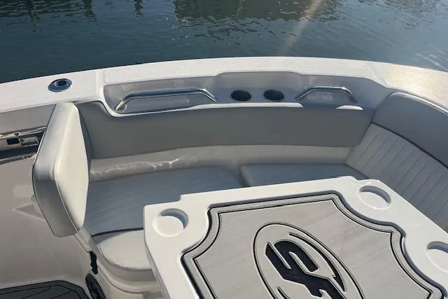 Slide: The Image of 2023 Sea Fox 228 Commander boat interior with seating and table, docked by the water. - 10