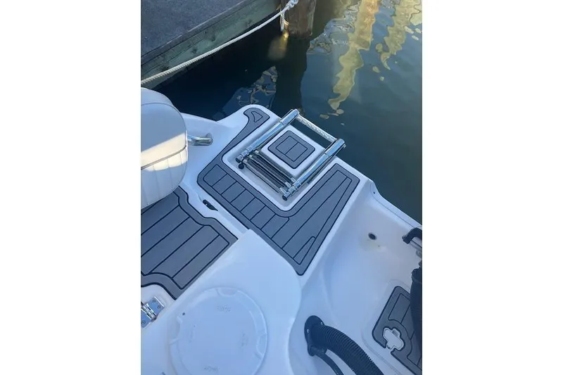 Slide: The Image of 2023 Sea Fox 228 Commander boat deck with ladder, docked by water. - 7