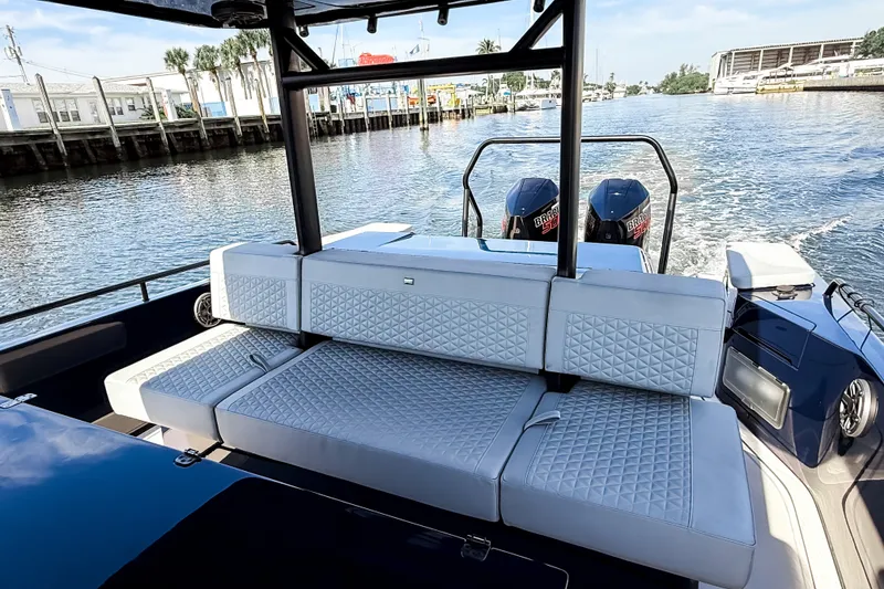 Slide: The Image of The image shows the stern of a BRABUS Shadow 1000 ST boat with luxurious cushioned seating and two outboard engines on a waterway. - 33