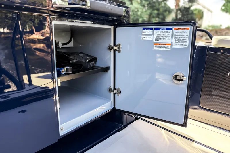 Slide: The Image of An open storage compartment on a 2024 BRABUS Shadow 1000 ST boat, featuring shelves and warning labels. - 21