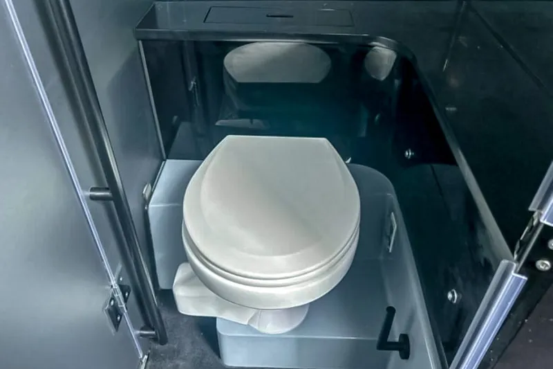Slide: The Image of The image shows a modern boat toilet with a white seat and dark surfaces. - 47