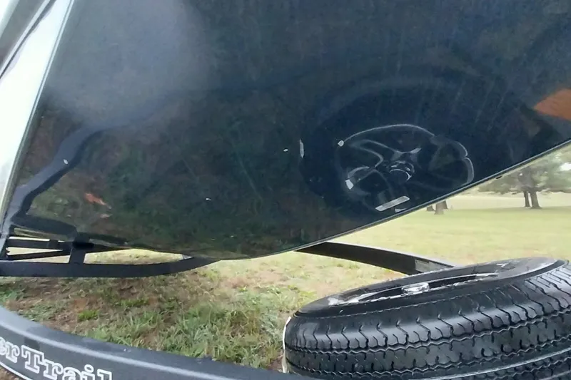 Slide: The Image of 2024 Ranger RT198P boat underside with trailer and spare tire on grassy field. - 12