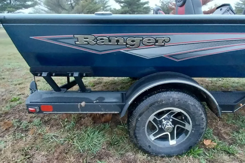 Slide: The Image of 2024 Ranger RT198P boat trailer with logo, parked on grass. - 18