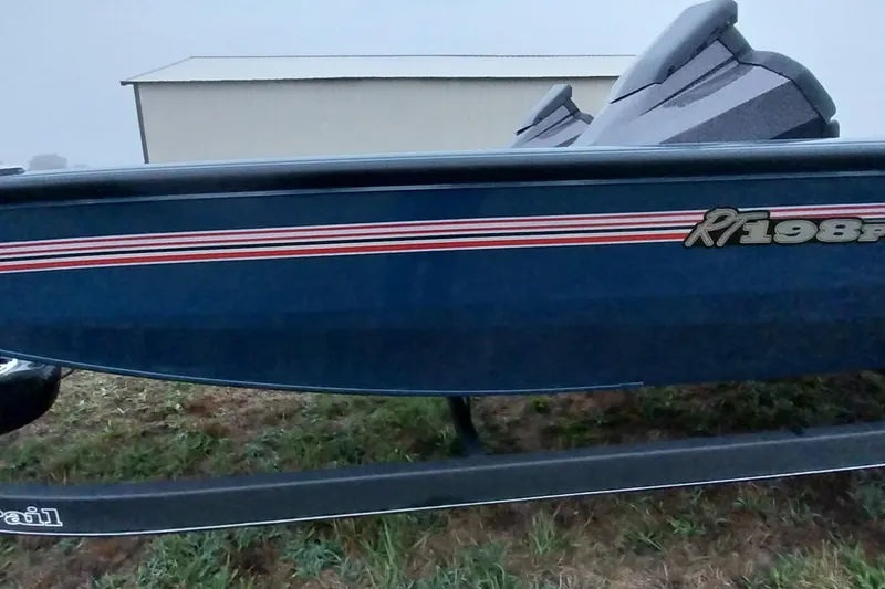 Slide: The Image of 2024 Ranger RT198P boat with blue hull and red stripes, parked on grass. - 43