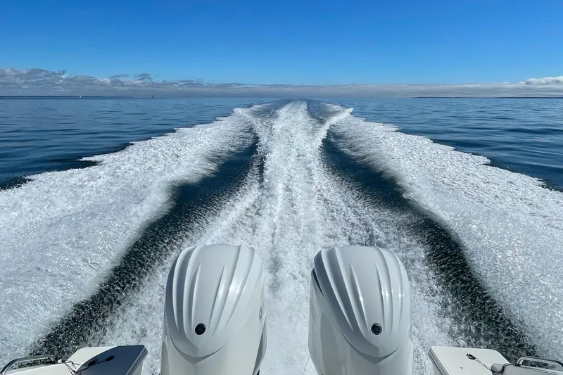 Slide: The Image of 2023 Pursuit S 328 Sport boat creating wake on open water under clear blue sky. - 11