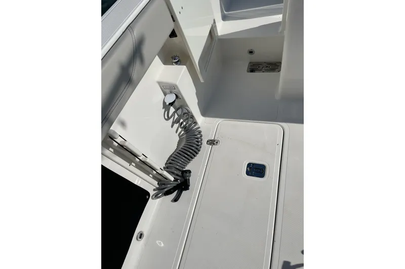 Slide: The Image of 2023 Pursuit S 328 Sport boat deck with storage compartment and coiled hose. - 26