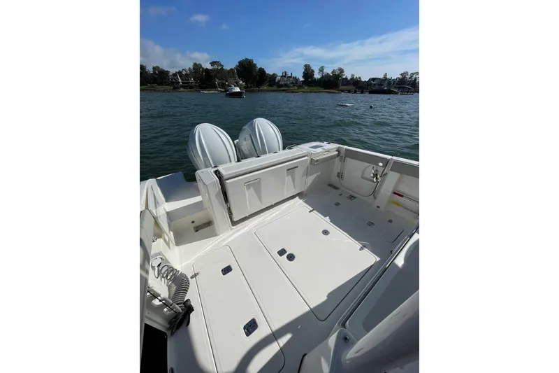 Slide: The Image of 2023 Pursuit S 328 Sport boat deck with dual engines on a sunny day. - 28