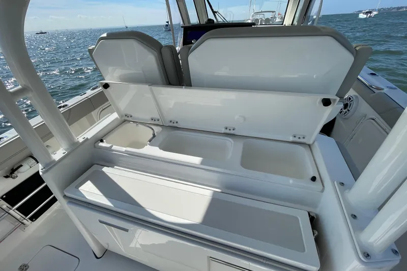 Slide: The Image of 2023 Pursuit S 328 Sport boat interior with open storage compartments, ocean view. - 33