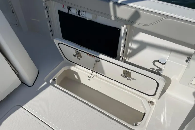 Slide: The Image of 2023 Pursuit S 328 Sport boat storage compartment with open hatch and latch. - 36