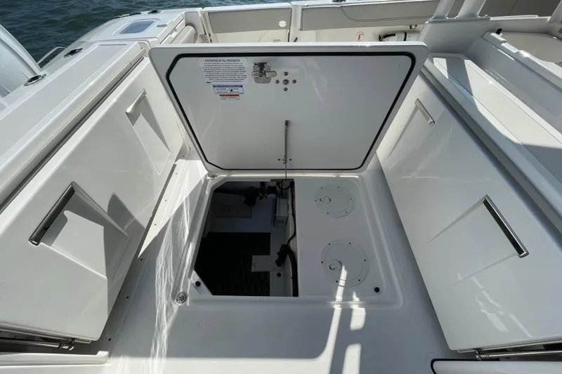 Slide: The Image of 2023 Pursuit S 328 Sport boat storage compartment with open hatch, revealing interior details. - 38