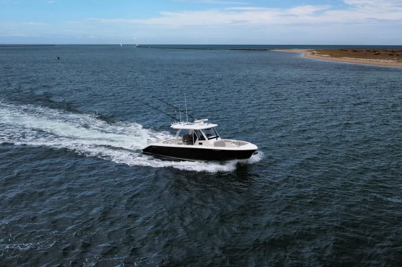 Slide: The Image of 2023 Pursuit S 328 Sport boat cruising on open water under a clear sky. - 5