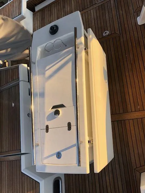 Slide: The Image of Beneteau Oceanis 46.1 yacht deck with wooden flooring, featuring a white storage compartment, 2023 model. - 23