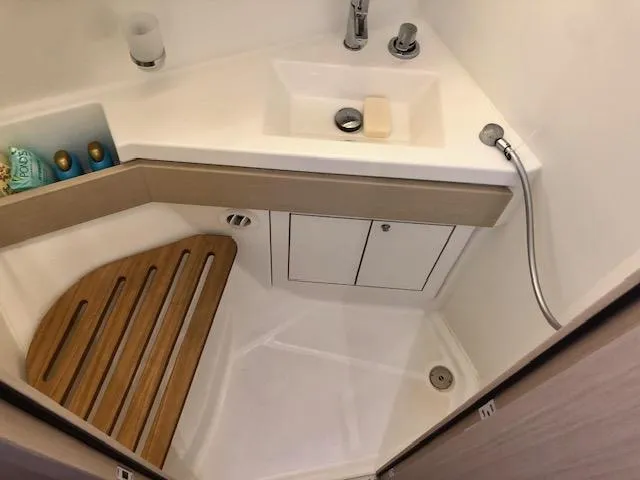 Slide: The Image of Compact bathroom in 2023 Beneteau Oceanis 46.1 yacht with sink, shower, and wooden floor mat. - 43