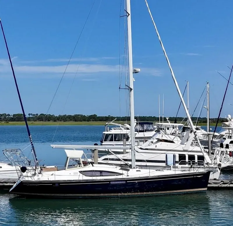 The Image of 2012 Jeanneau 50 DS sailboat docked in a marina under clear blue skies. - 0
