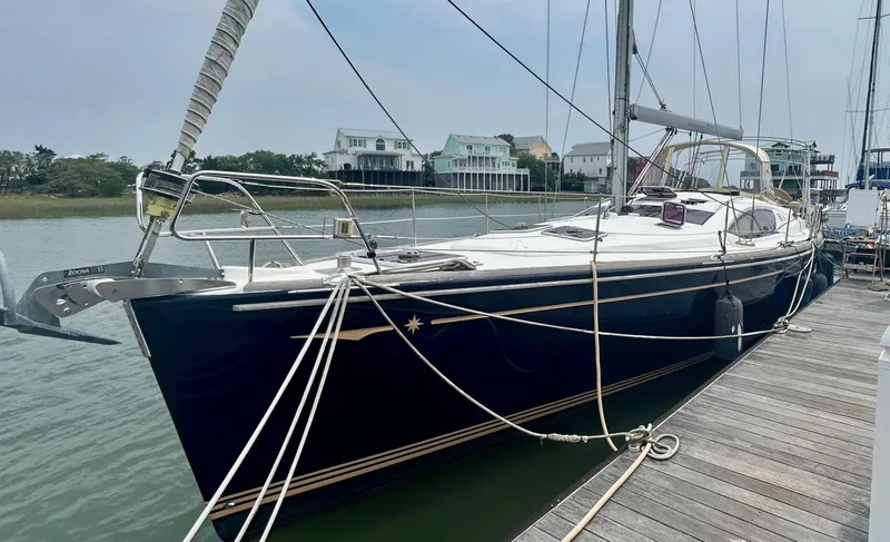 Slide: The Image of 2012 Jeanneau 50 DS sailboat docked, showcasing sleek design and modern features. - 2