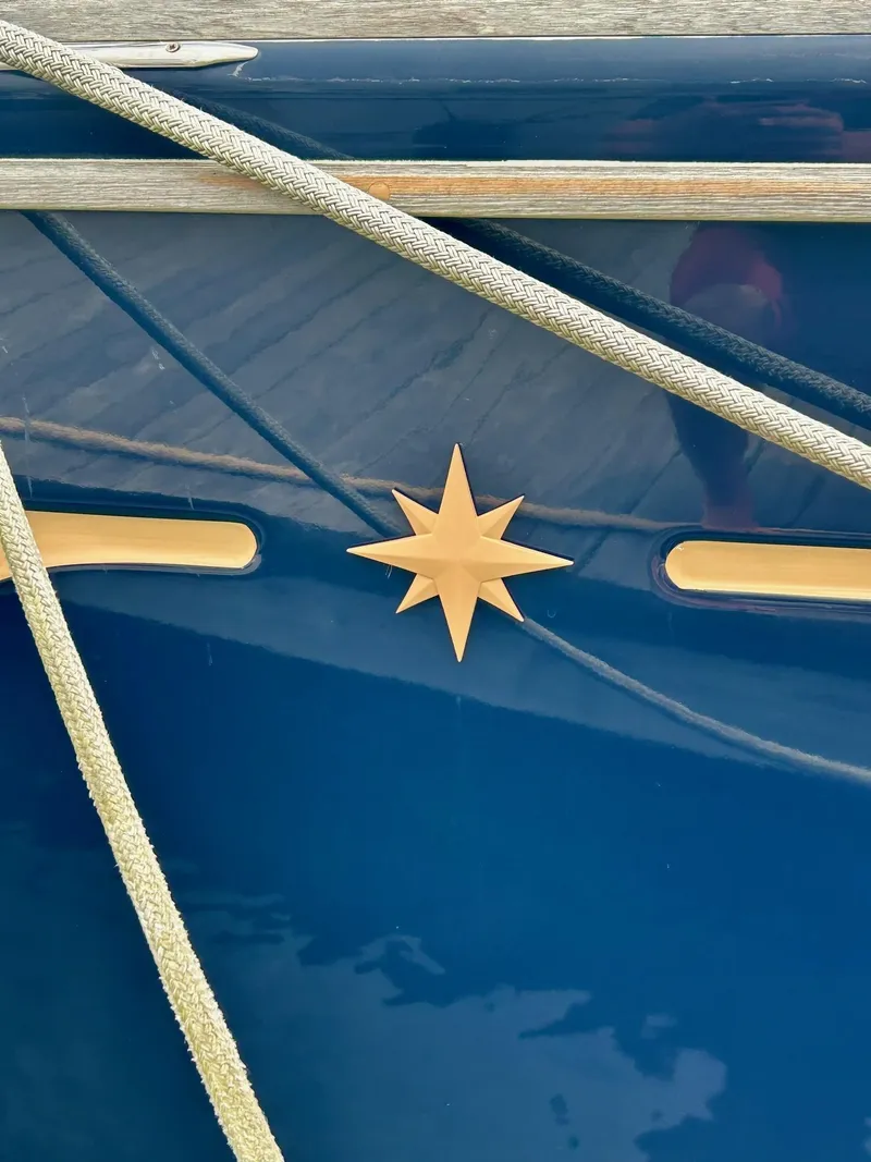 Slide: The Image of Jeanneau 50 DS 2012 sailboat with star emblem and ropes on blue hull. - 5