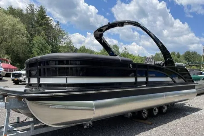 The Image of 2024 Bennington RFBASR pontoon boat on trailer under a cloudy sky. - 0