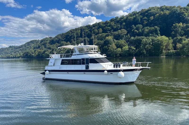 The Image of 1997 Pluckebaum 60 Motor Yacht cruising on a scenic lake with lush green hills. - 0