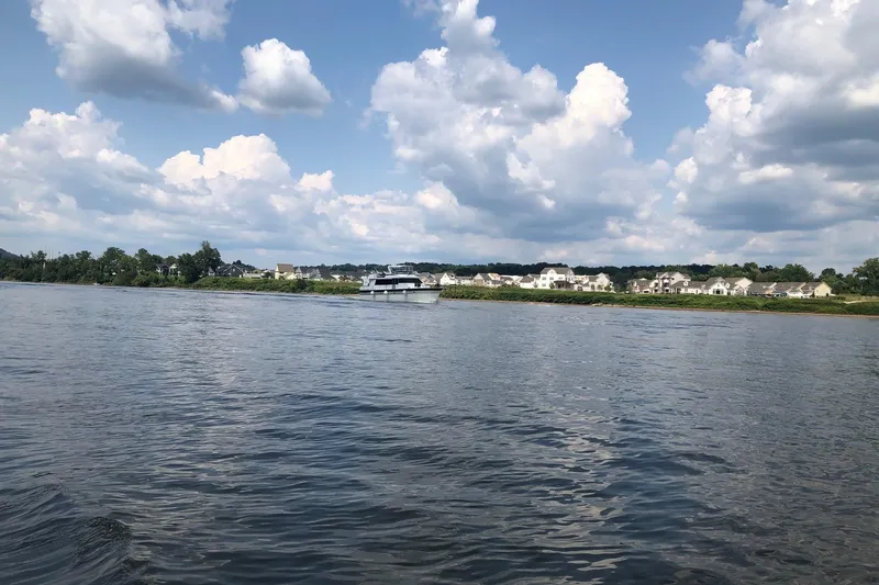 Slide: The Image of 1997 Pluckebaum 60 Motor Yacht on a serene river under a cloudy sky. - 4