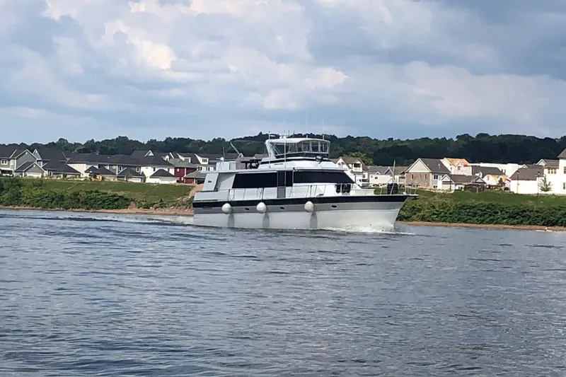 Slide: The Image of 1997 Pluckebaum 60 Motor Yacht cruising near residential shoreline under cloudy sky. - 5