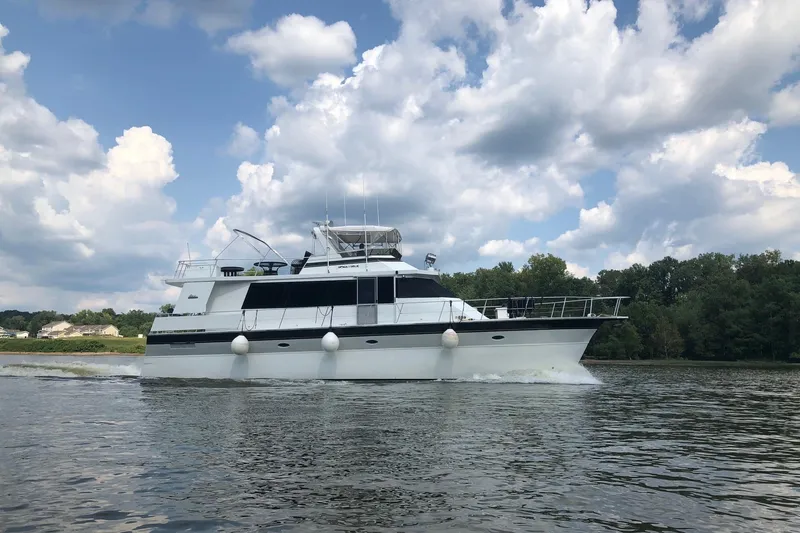 Slide: The Image of 1997 Pluckebaum 60 Motor Yacht cruising on a serene lake under a cloudy sky. - 6