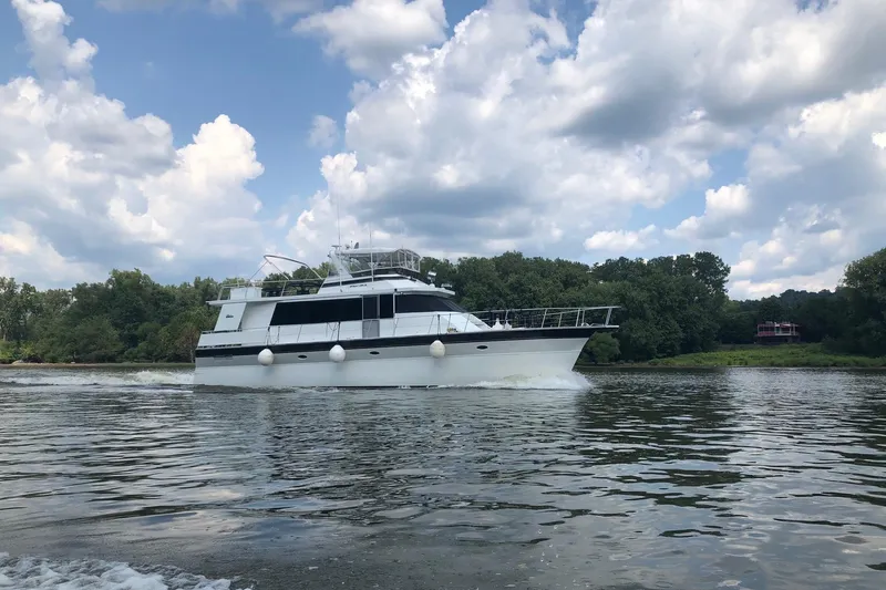 Slide: The Image of 1997 Pluckebaum 60 Motor Yacht cruising on a scenic river under a partly cloudy sky. - 7