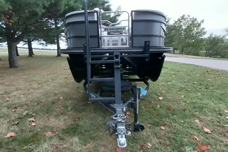 Slide: The Image of 2020 Ranger 2500LS boat on trailer, parked on grassy area with trees in background. - 17