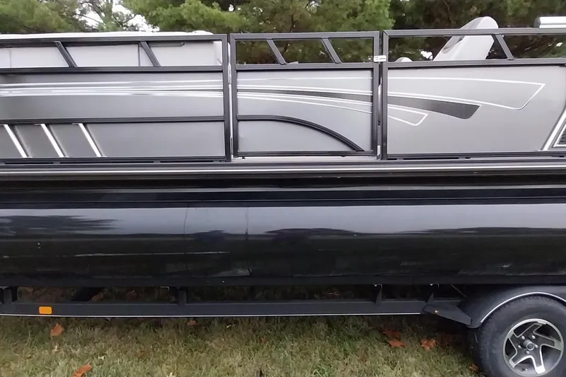 Slide: The Image of 2020 Ranger 2500LS pontoon boat side view with sleek black and gray design. - 28