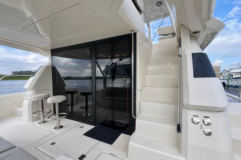 Slide: The Image of 2019 Aquila 44 yacht interior with bar stools and staircase, docked by the water. - 17