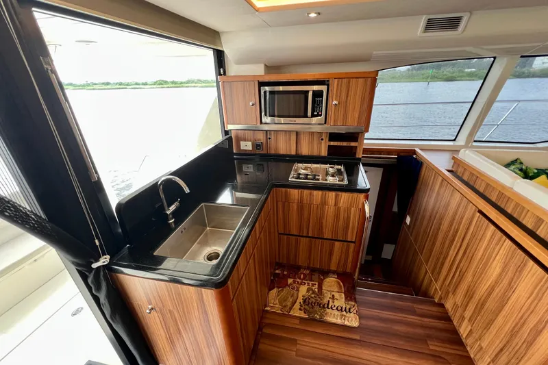 Slide: The Image of Luxurious 2019 Aquila 44 yacht kitchen with wood cabinetry, sink, stove, and microwave. - 43